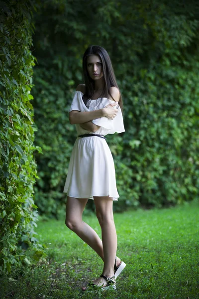 Portrait complet d'une belle jeune femme caucasienne en robe blanche aux épaules ouvertes, à la peau propre, aux cheveux longs et au maquillage décontracté — Photo