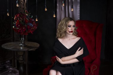 Cadılar Bayramı makyaj ve kanlı yüz sanat ile siyah elbiseli güzel genç sarışın kadın