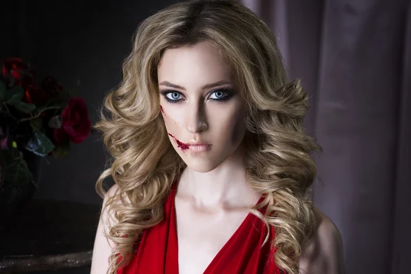Bella giovane donna bionda in abito rosso con Halloween make up e sanguinosa arte del viso — Foto Stock