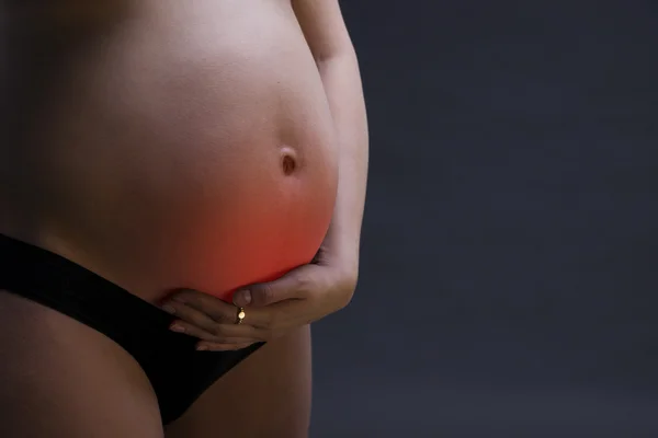 Femme enceinte caucasienne en lingerie noire avec douleur abdominale sur fond studio gris avec espace de copie — Photo