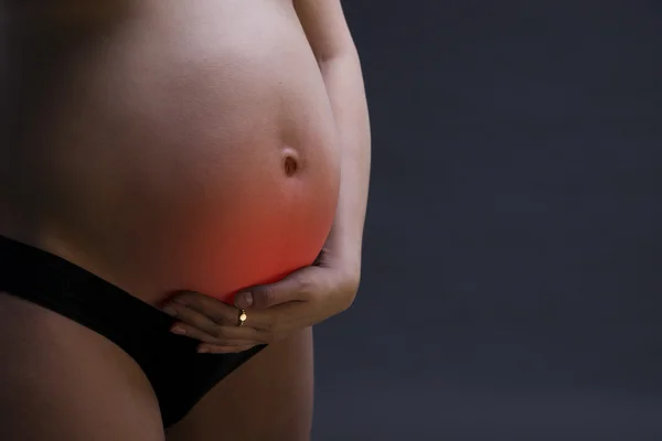 Caucasian pregnant woman in black lingerie with abdominal pain on gray studio background with copy space — Stock Photo, Image