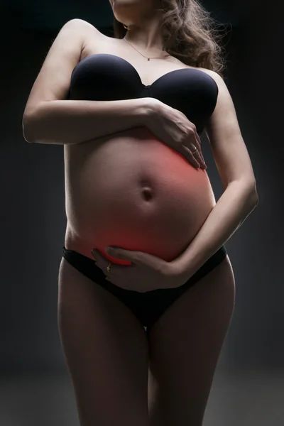 Caucazian gravidă femeie în lenjerie neagră cu dureri abdominale pe fundal studio gri — Fotografie, imagine de stoc