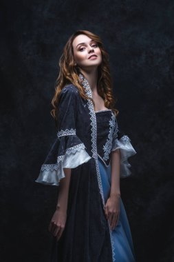 Rönesans elbiseli mutlu güzel kadın soyut koyu arka plan, stüdyo çekimi