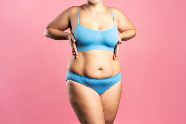 Fat woman with large breasts in a push-up bra on pink background,  overweight female body Stock Photo