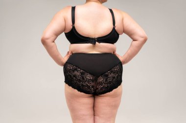 Şişman kalçaları ve kalçaları olan şişman bir kadın, gri arka planda obez bir kadın vücudu, stüdyo çekimi.