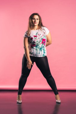 Artı, pembe arka planda günlük kıyafet modeli, vücut pozitifliği.