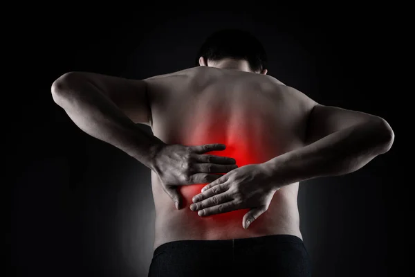 Back pain, kidney inflammation, ache in man\'s body on black background, painful area highlighted in red