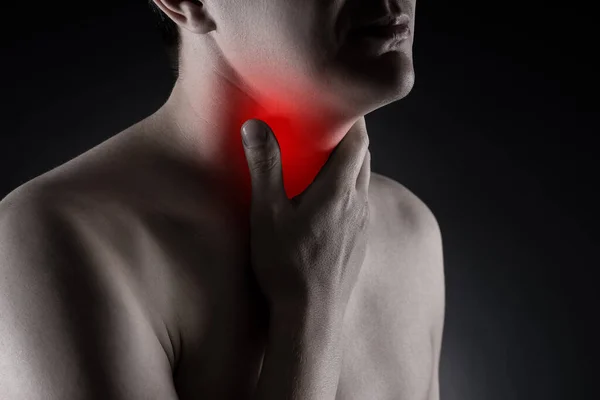 Sore throat, men with pain in neck on black background, painful area highlighted in red