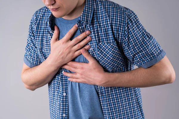 Heart attack, diseases of the cardiovascular system, man with chest pain on gray background, studio shot
