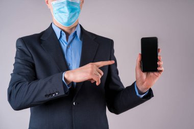 Gri arka planda cep telefonu maskeli bir ofis çalışanı, koronavirüs konsepti