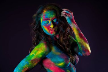 Siyah arka planda parlak renkli vücut sanatı, tozlu boyalarla boyanmış seksi çıplak kadın, stüdyo çekimi.