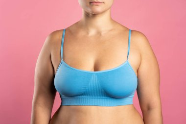 Mavi sutyenli büyük doğal göğüsler. Pembe arka planda, stüdyo çekimi.