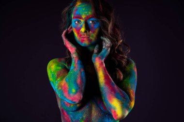 Yaratıcı makyaj, siyah arka planda parlak renkli vücut sanatı, pudra boyasıyla boyanmış seksi çıplak kadın, stüdyo çekimi.