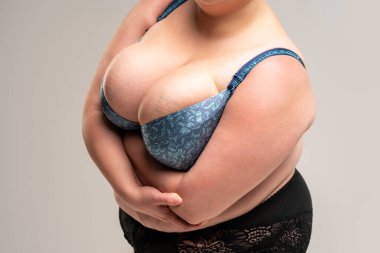 Mavi sutyenli büyük göğüsler, gri arka planda obezite kadın vücudu, stüdyo çekimi.