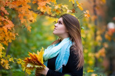 Beautiful woman in autumn, cute plus size model outdoors, portrait with yellow leaves