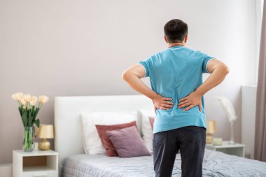 Sırt ağrısı, böbrek iltihabı, evde sırt ağrısı çeken bir adam, kırmızı ile işaretlenmiş acı veren bir bölge.