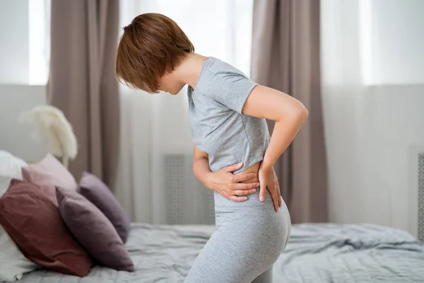 Back pain, kidney inflammation, woman suffering from backache at home, health problems concept