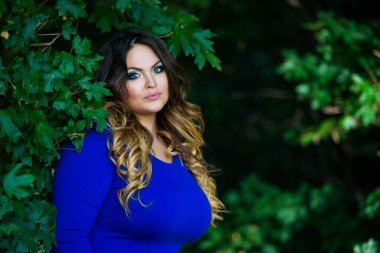 Mavi elbiseli mutlu artı beden manken, sonbahar parkında sarı yaprakların arasında şişman kadın, doğada güzellik.