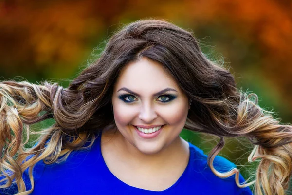 幸せなプラスサイズモデルで青ドレス屋外 脂肪女性で秋公園で黄色の葉 美しい髪型と化粧 — ストック写真