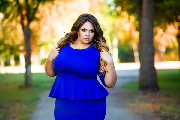 外面穿蓝色衣服的美女加模特 秋天公园里黄叶丛中的胖女人 漂亮的发型和妆容 — 图库照片