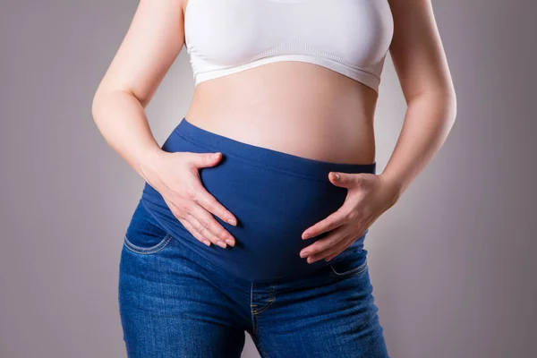 Mateřské Oblečení Těhotná Žena Modrých Džínách Šedém Pozadí Těhotenský Koncept — Stock fotografie
