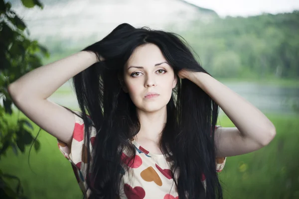 Portret van een mooie jonge vrouw op de achtergrond van de heuvel — Stockfoto