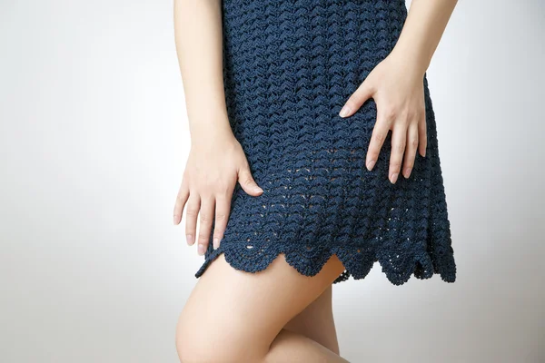Young woman in a short skirt knitted on a gray background — Stock Photo, Image
