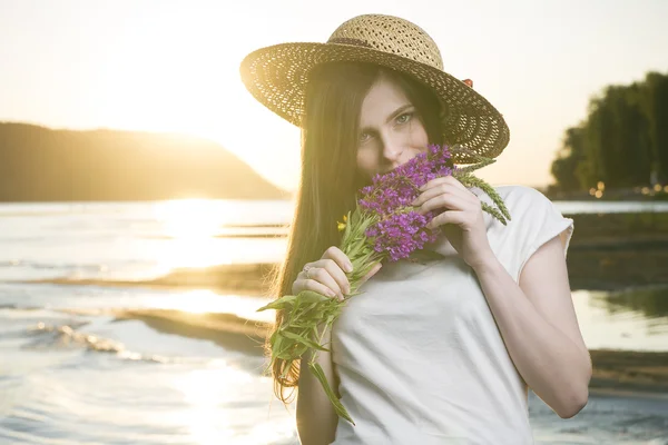 Porträt einer schönen Frau mit Hut vor dem Hintergrund eines Sonnenuntergangs — Stockfoto