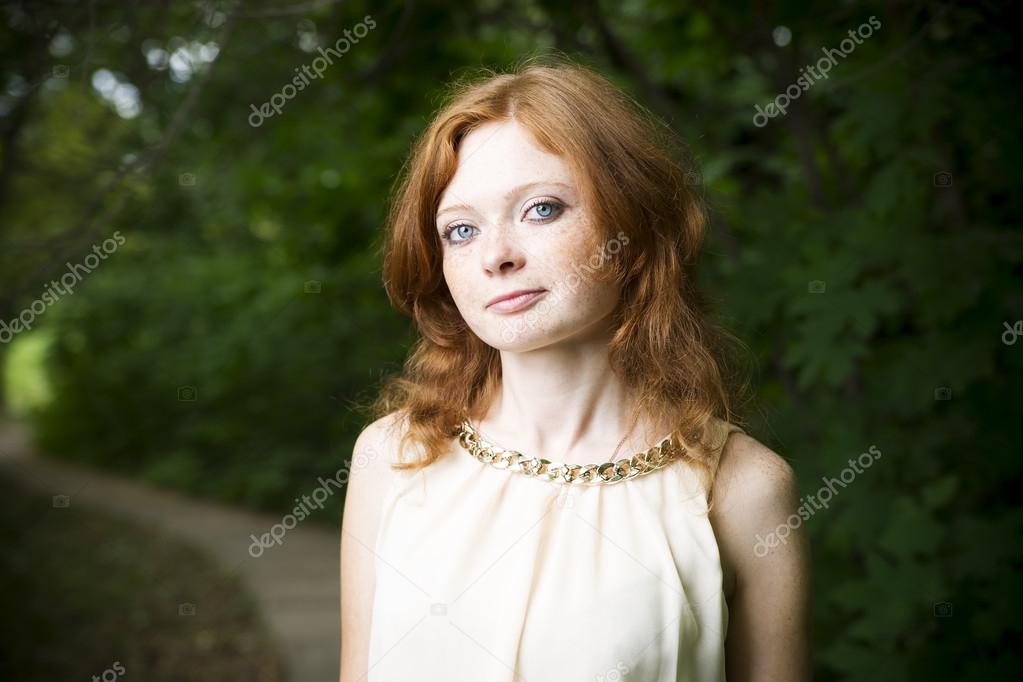 Portrait of redhead girl with blue eyes on nature