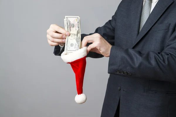 Zakenman geld steken in een kerstmuts — Stockfoto