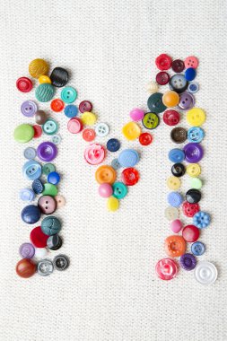 Çeşitli şekil ve renk düğmelerinin alfabenin M harfi