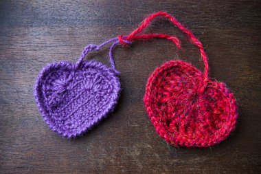 Ahşap arka plan üzerinde örme kırmızı ve mor Kalpler