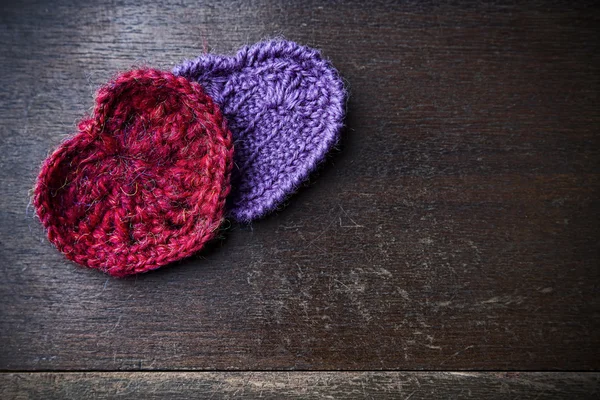 Corazones rojos y morados de punto sobre un fondo de madera — Foto de Stock