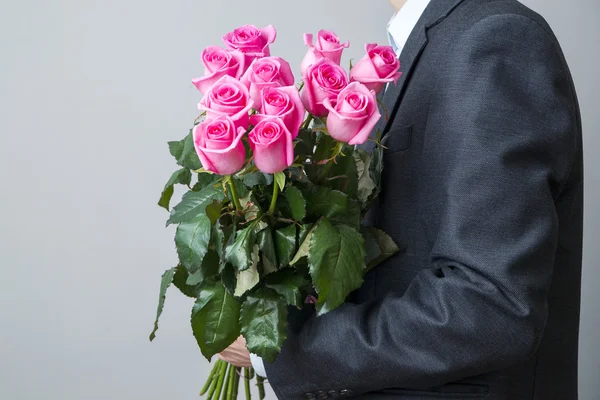 Man in suit with bouquet of pink roses