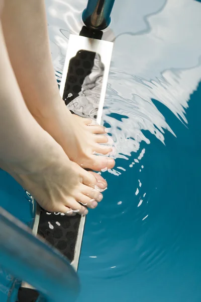 Belos pés femininos nos degraus da piscina — Fotografia de Stock