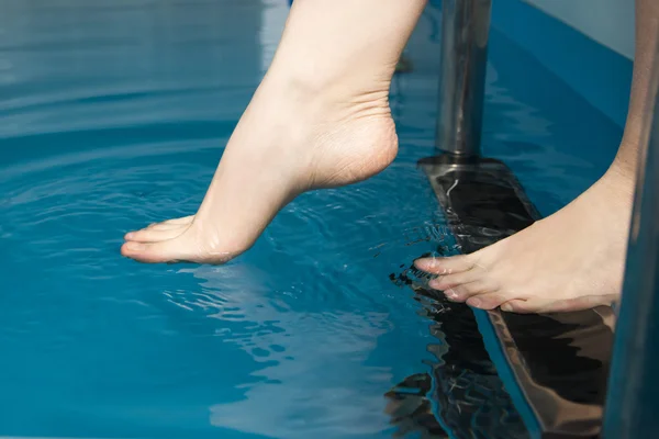Hermosos pies femeninos en las escaleras de la piscina — Foto de Stock