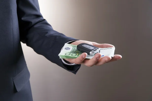 Бизнесмен использует ключи от машины и деньги — стоковое фото