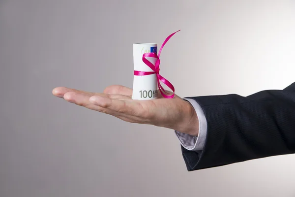 Pengar med rosett i manlig hand på en grå bakgrund — Stockfoto