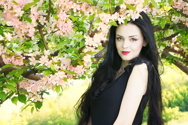 Beautiful young woman in blooming gardens — Stock Photo, Image