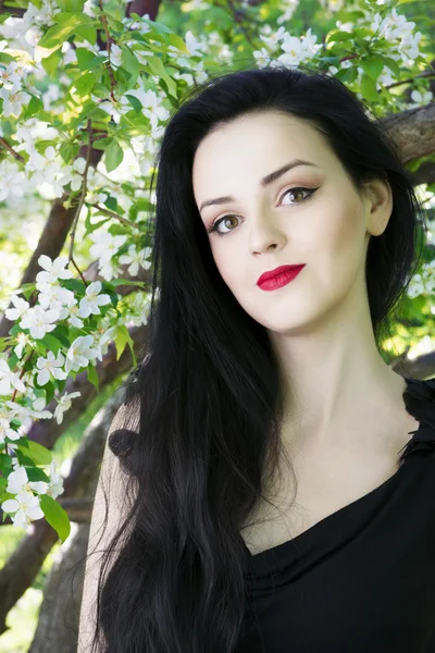 Beautiful young woman in blooming gardens — Stock Photo, Image