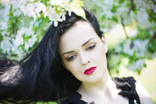 Beautiful young woman in blooming gardens — Stock Photo, Image