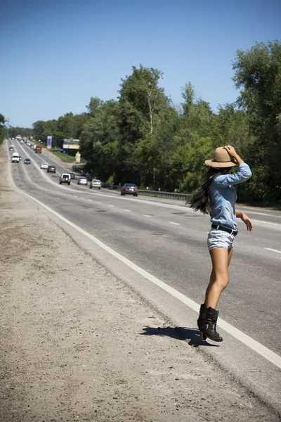 Молодая красивая женщина автостопом по дороге — стоковое фото