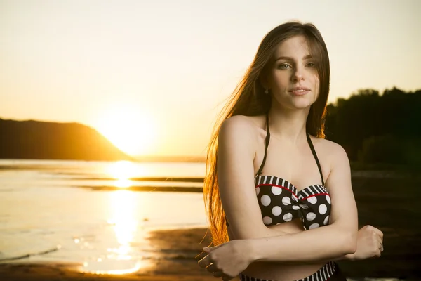 Mooie vrouw in bikini op zonsondergang achtergrond — Stockfoto