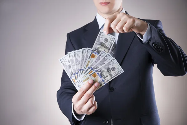 Businessman with money in studio on a gray background — Stock Photo, Image