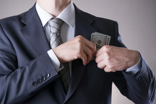 Geschäftsmann mit Geld im Atelier vor grauem Hintergrund — Stockfoto