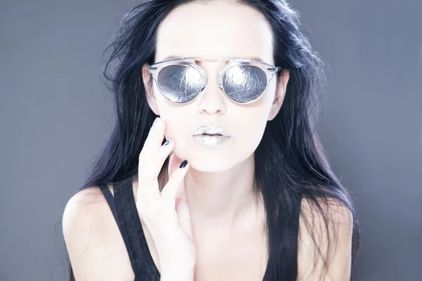Mooie vrouw fashion model portret in zonnebril met metallisch zilver lippen. Creatieve kapsel en make-up — Stockfoto
