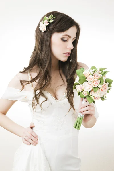 Hermosa novia en un vestido blanco con un ramo — Foto de Stock