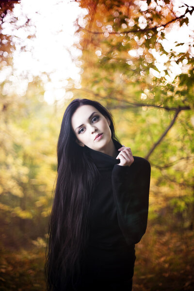 Beautiful woman with long black hair in autumn forest