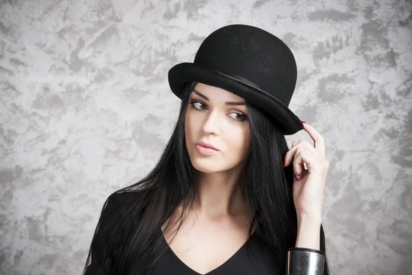 Portrait of a beautiful young woman in a black dress and bowler hat — Stock Photo, Image