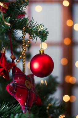 Şenlikli arka planda çam dallarında asılı parlak Noel kırmızı topu.